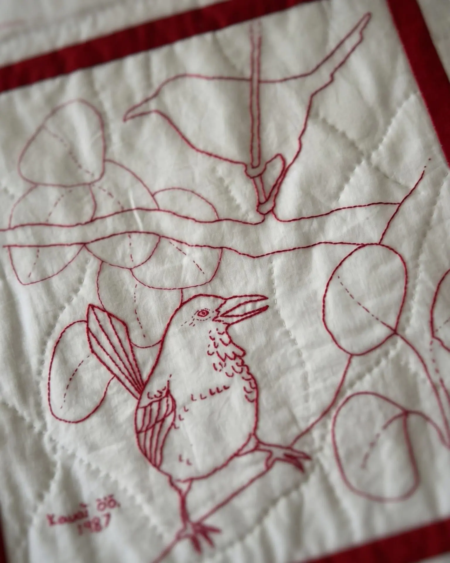 Embroidered birds on quilted fabric.
