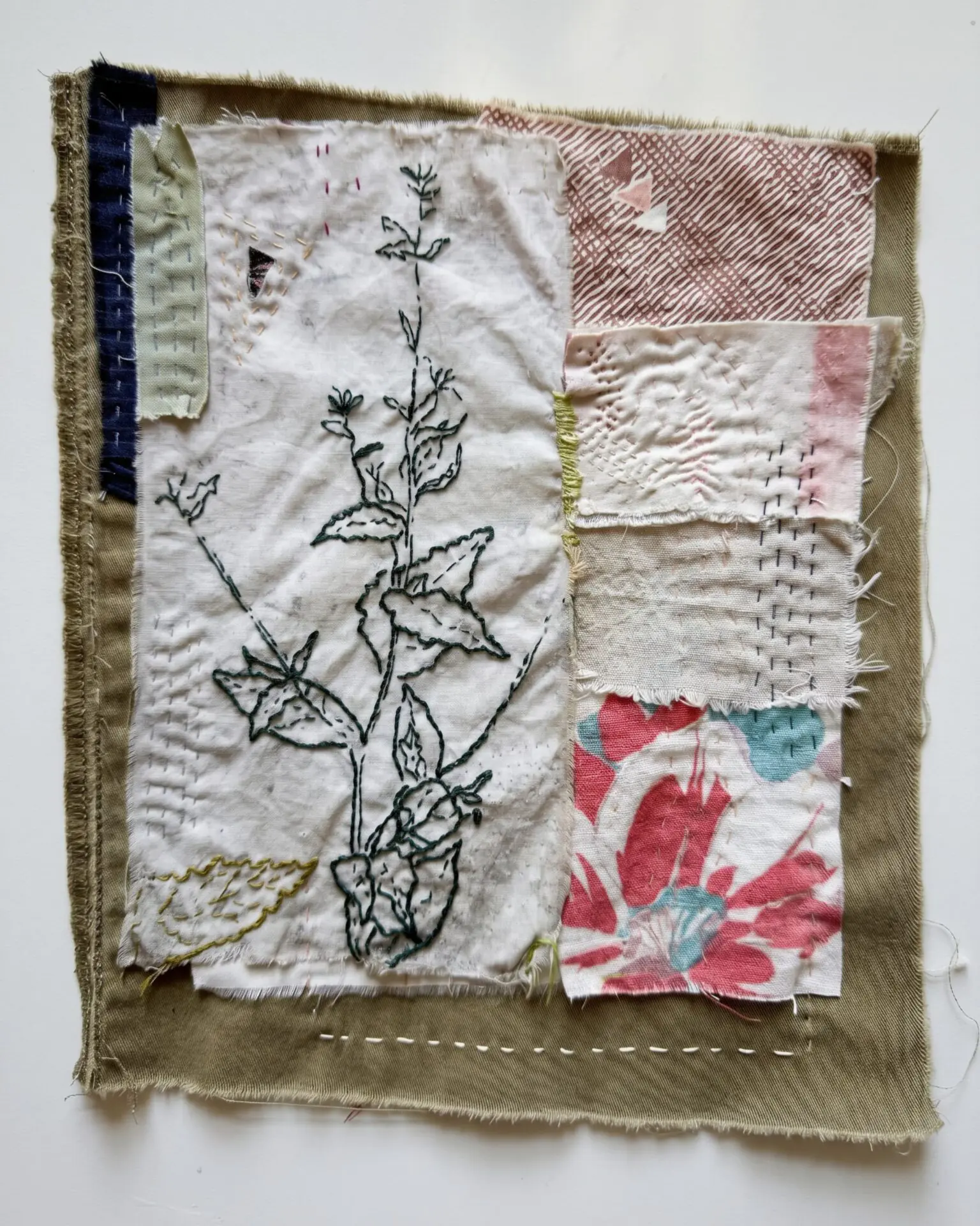 Textile art with floral embroidery patches.