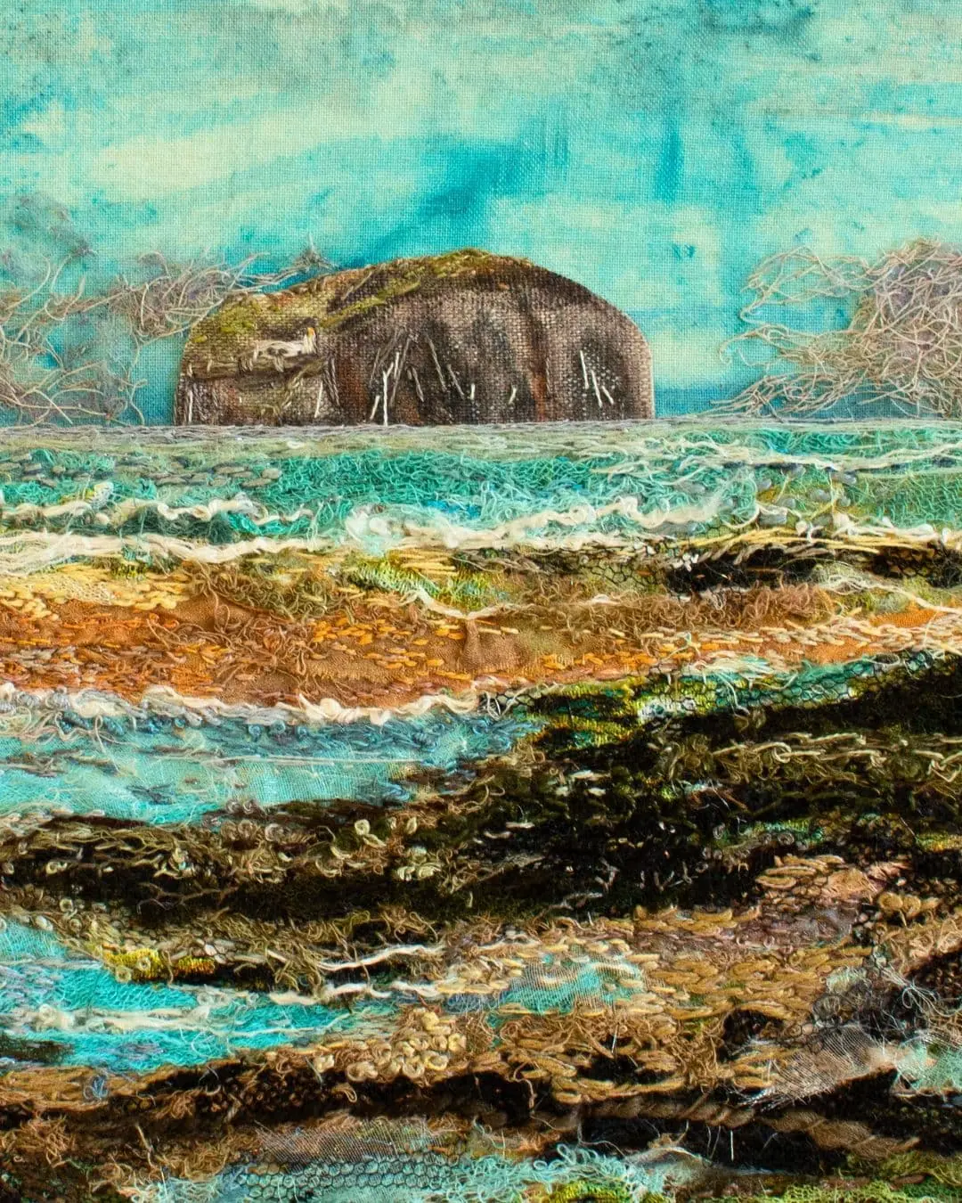 A thread painting of a large rock in a watery landscape