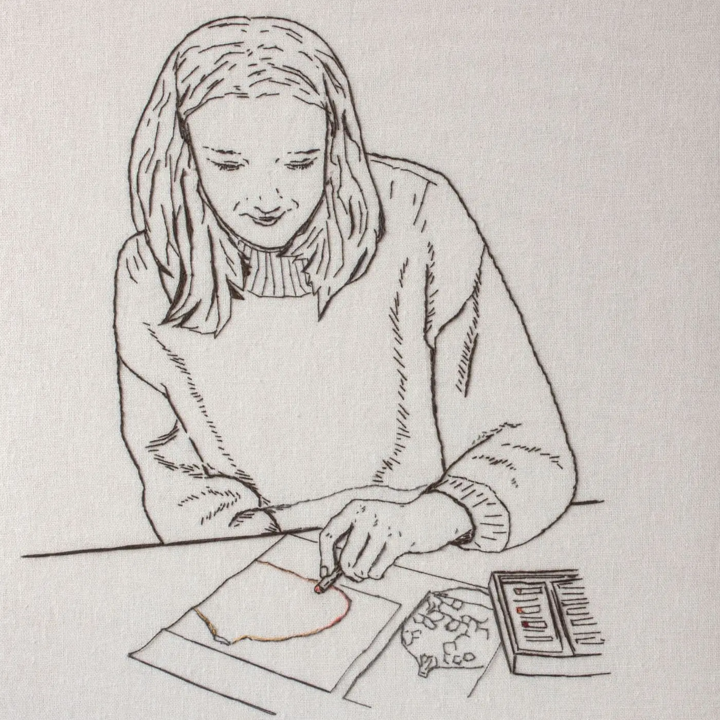 A stitched portrait of a woman drawing on a piece of paper