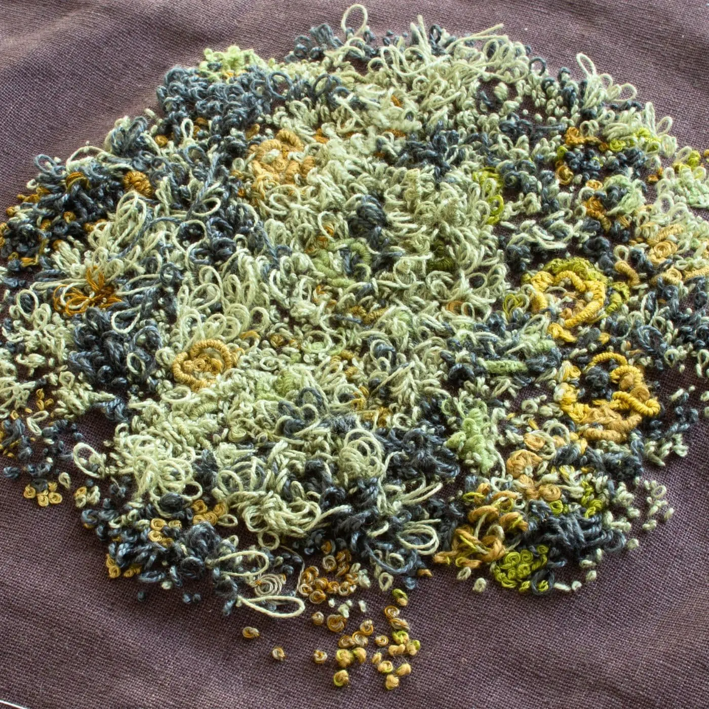 A stitched pile of threads on a fabric surface creating a tactile impression of Lichen