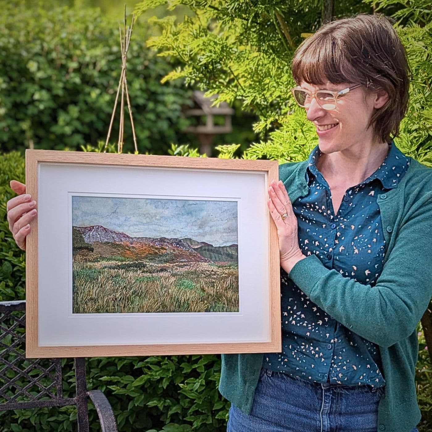 A textile collage hand stitched painting of scenery held by the artist Heidi Ingram