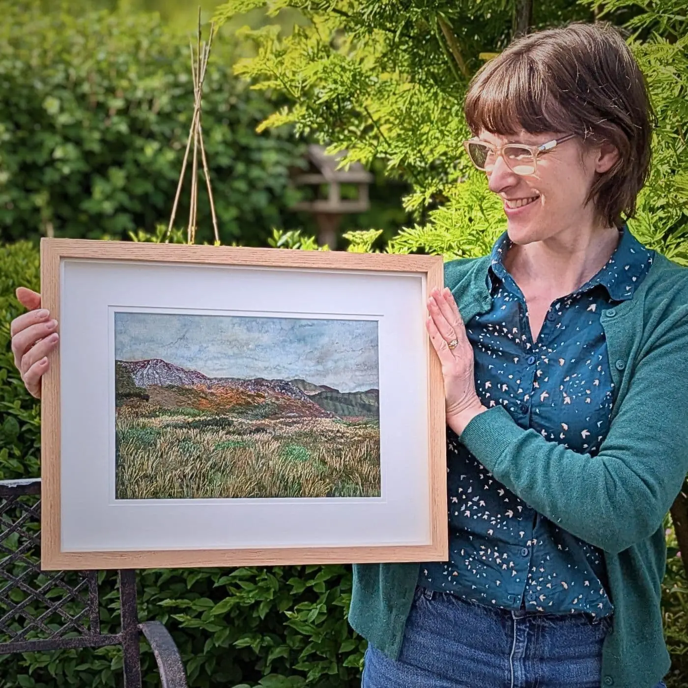 A textile collage hand stitched painting of scenery held by the artist Heidi Ingram