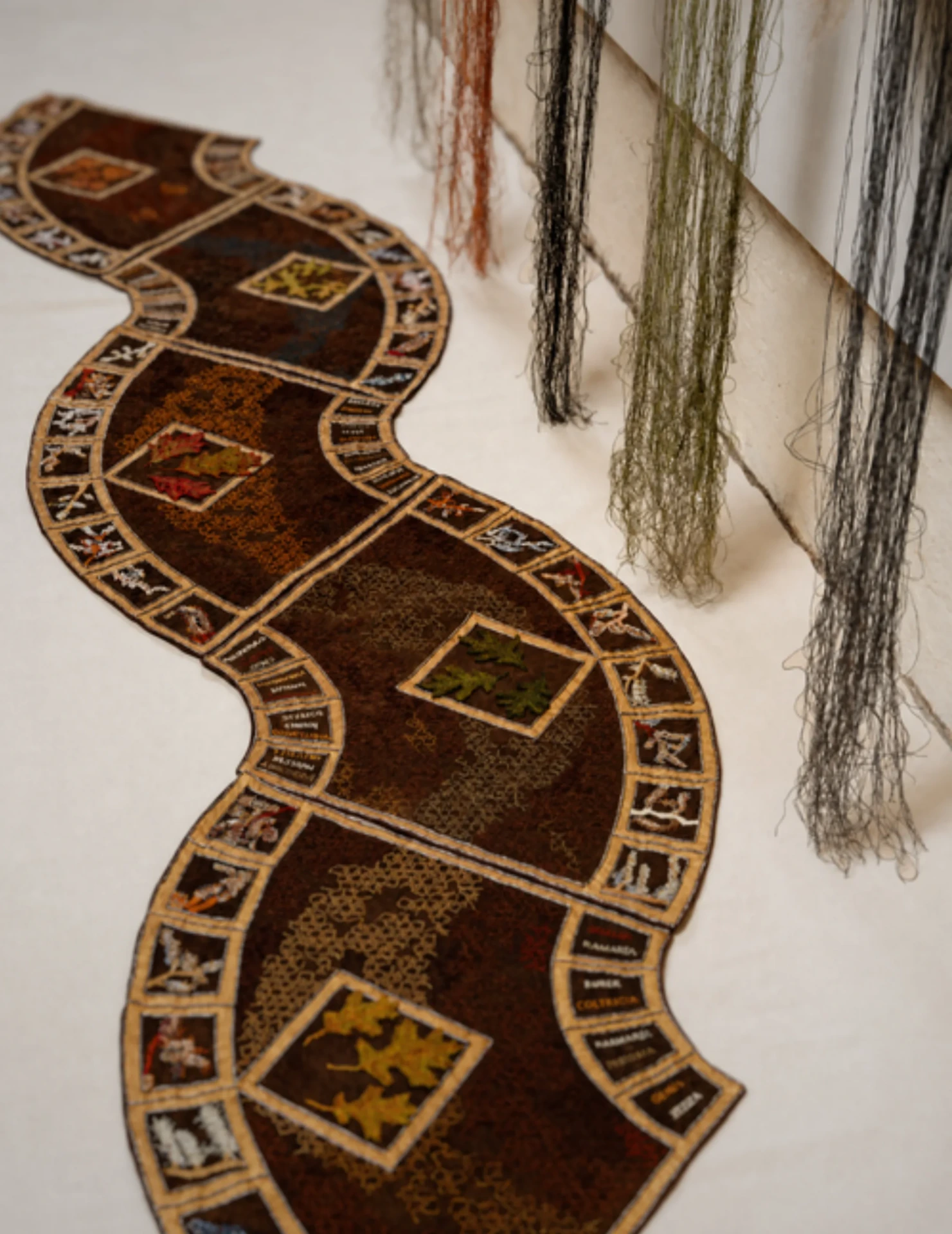 Intricate textile art with hanging threads.