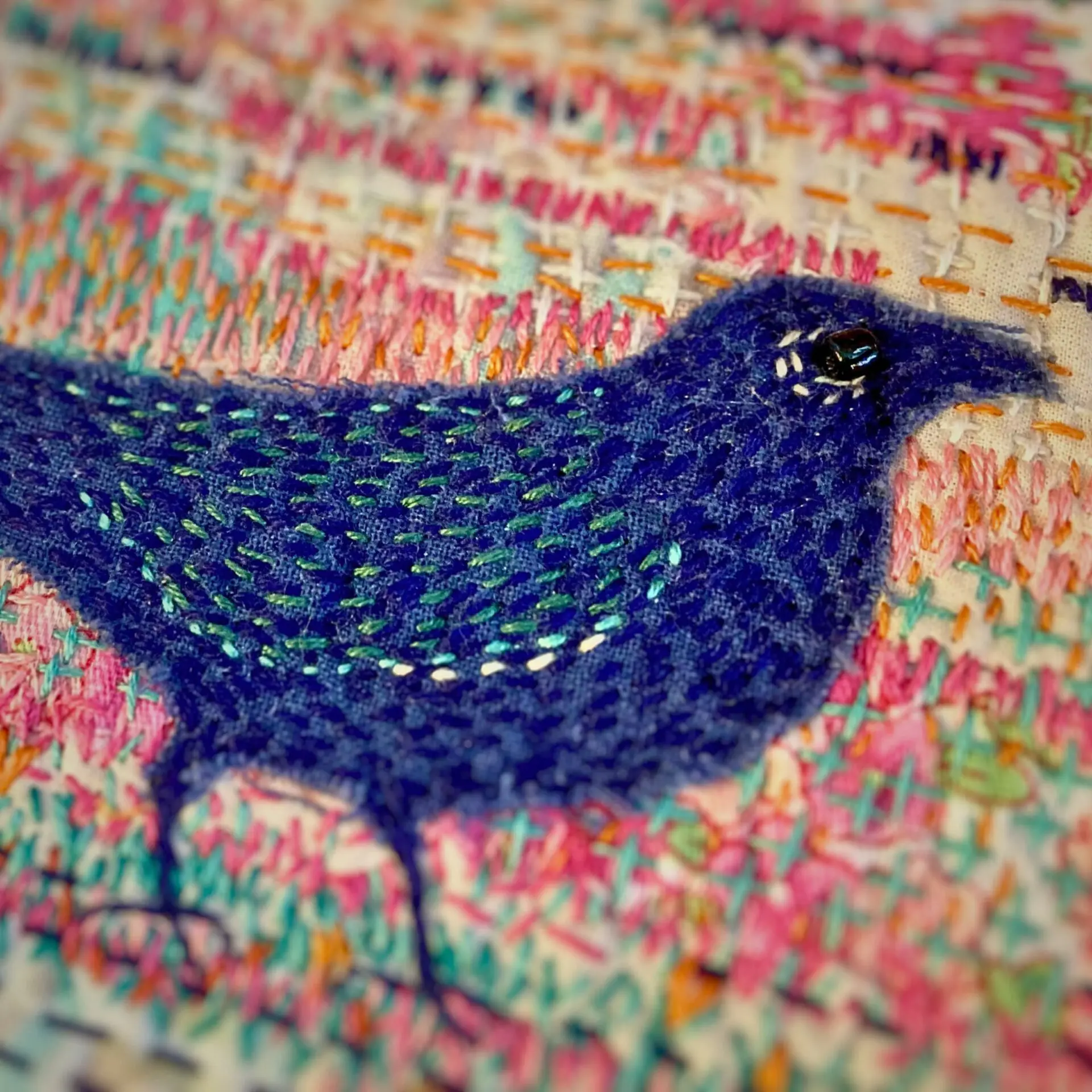 Embroidered blue bird on textured fabric