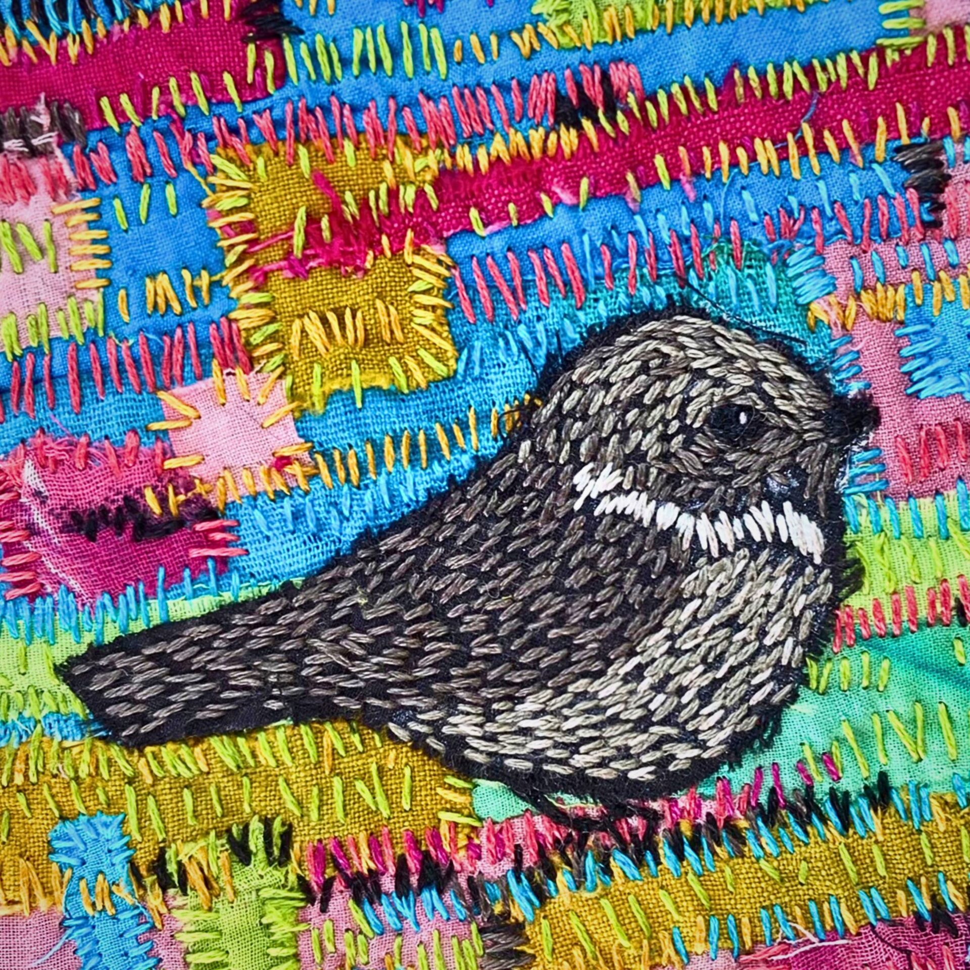 Embroidered bird on colourful fabric