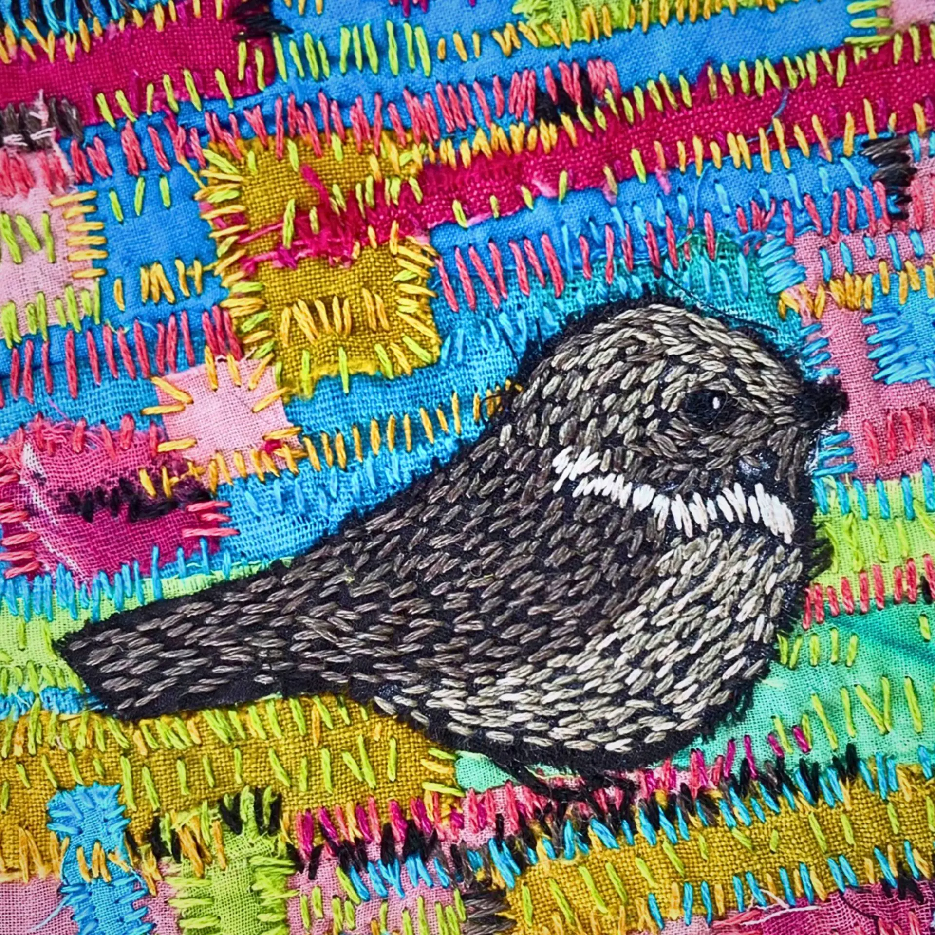 Embroidered bird on colourful fabric