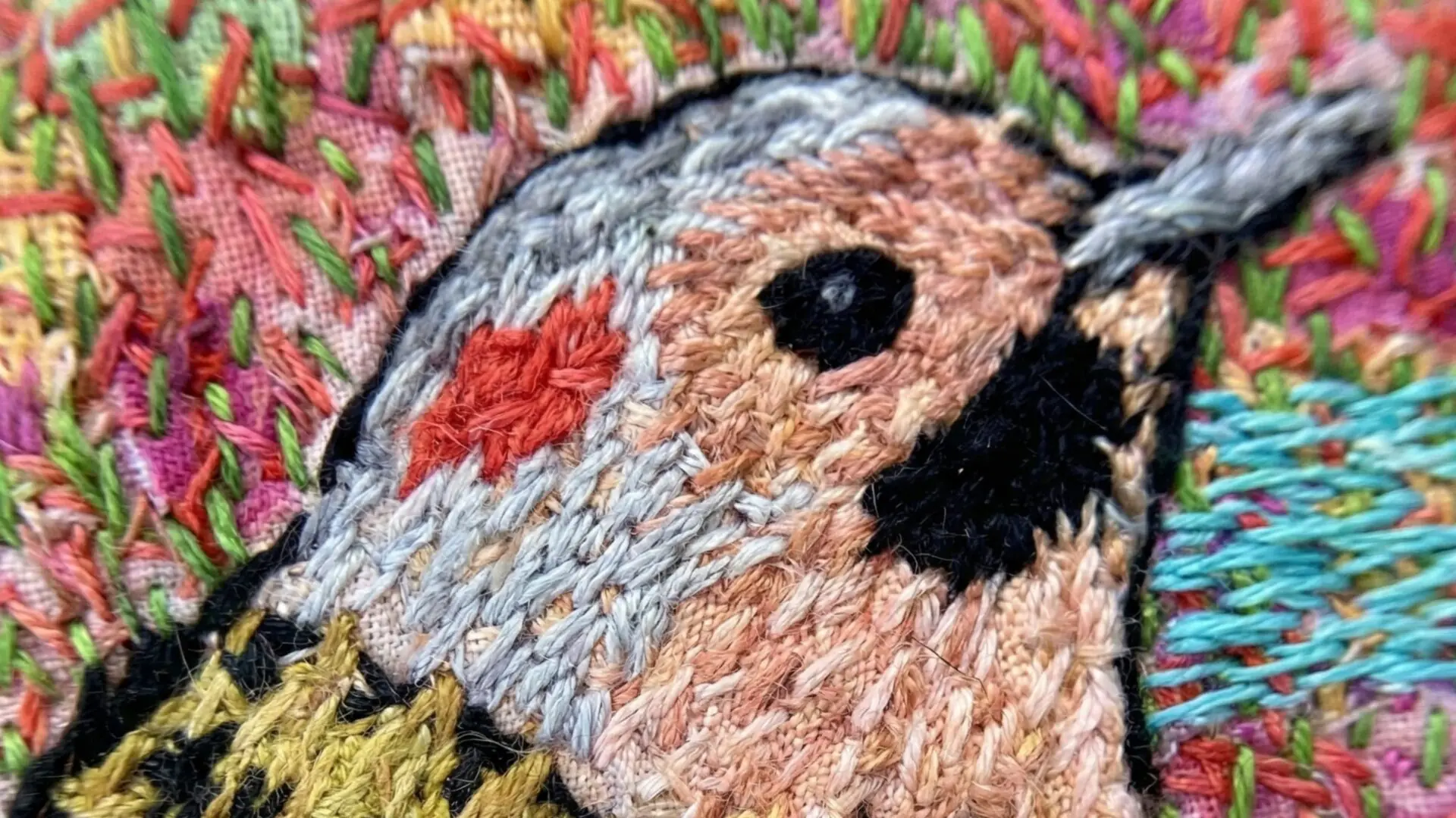 Colourful embroidery of a bird, close up.