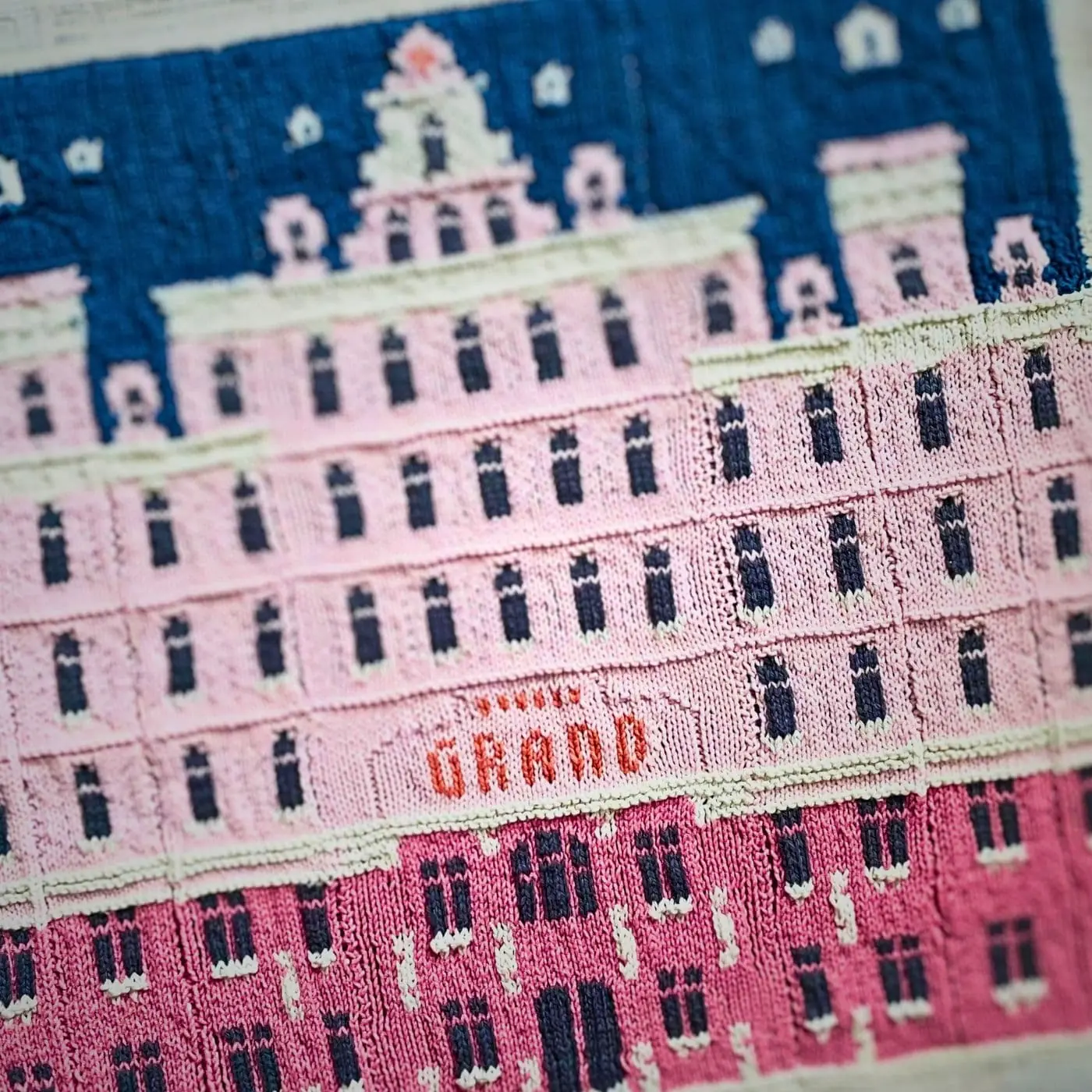 A knitted artwork of the 'Grand Budapest Hotel' a large pink building 