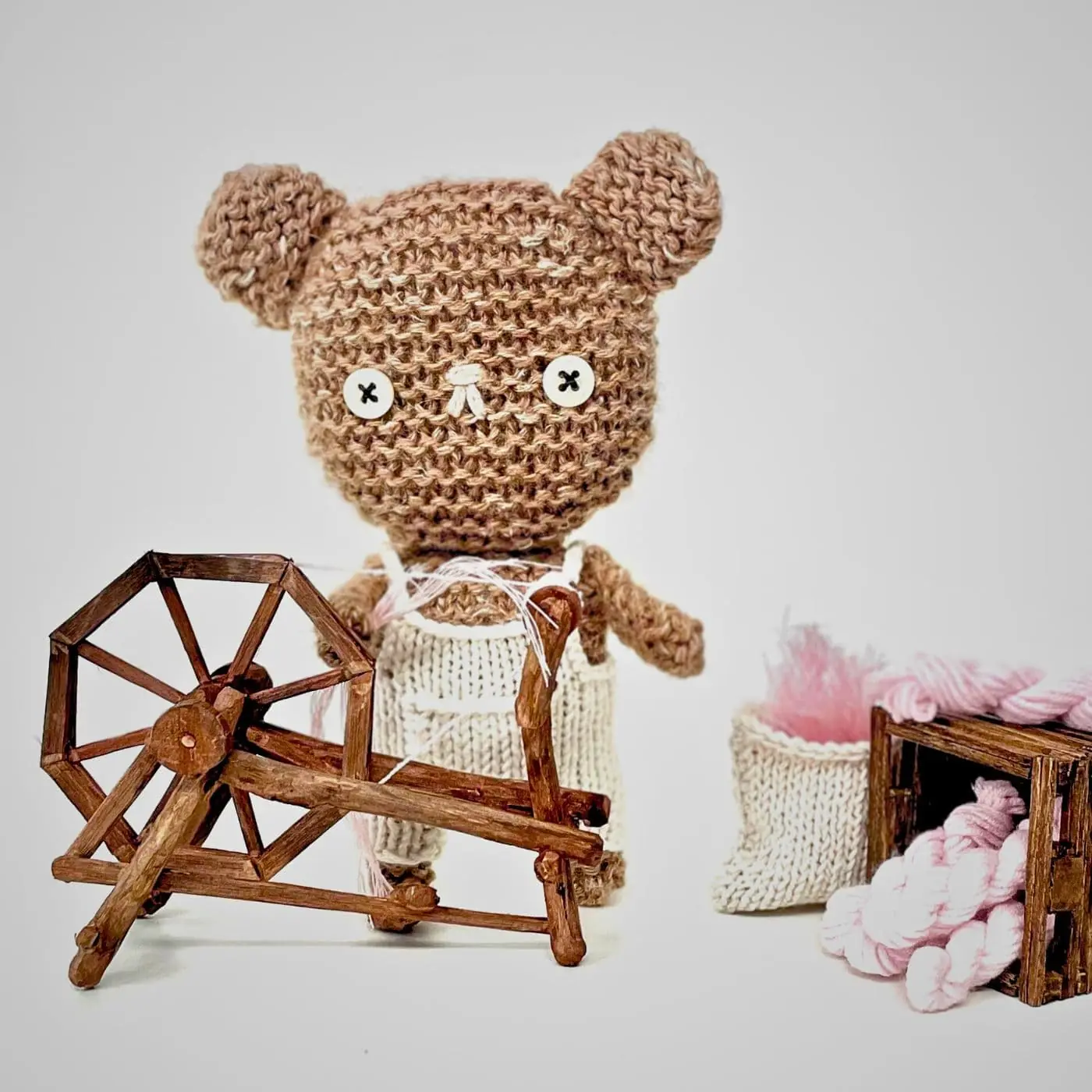 A knitted teddy bear with  a spinning wheel