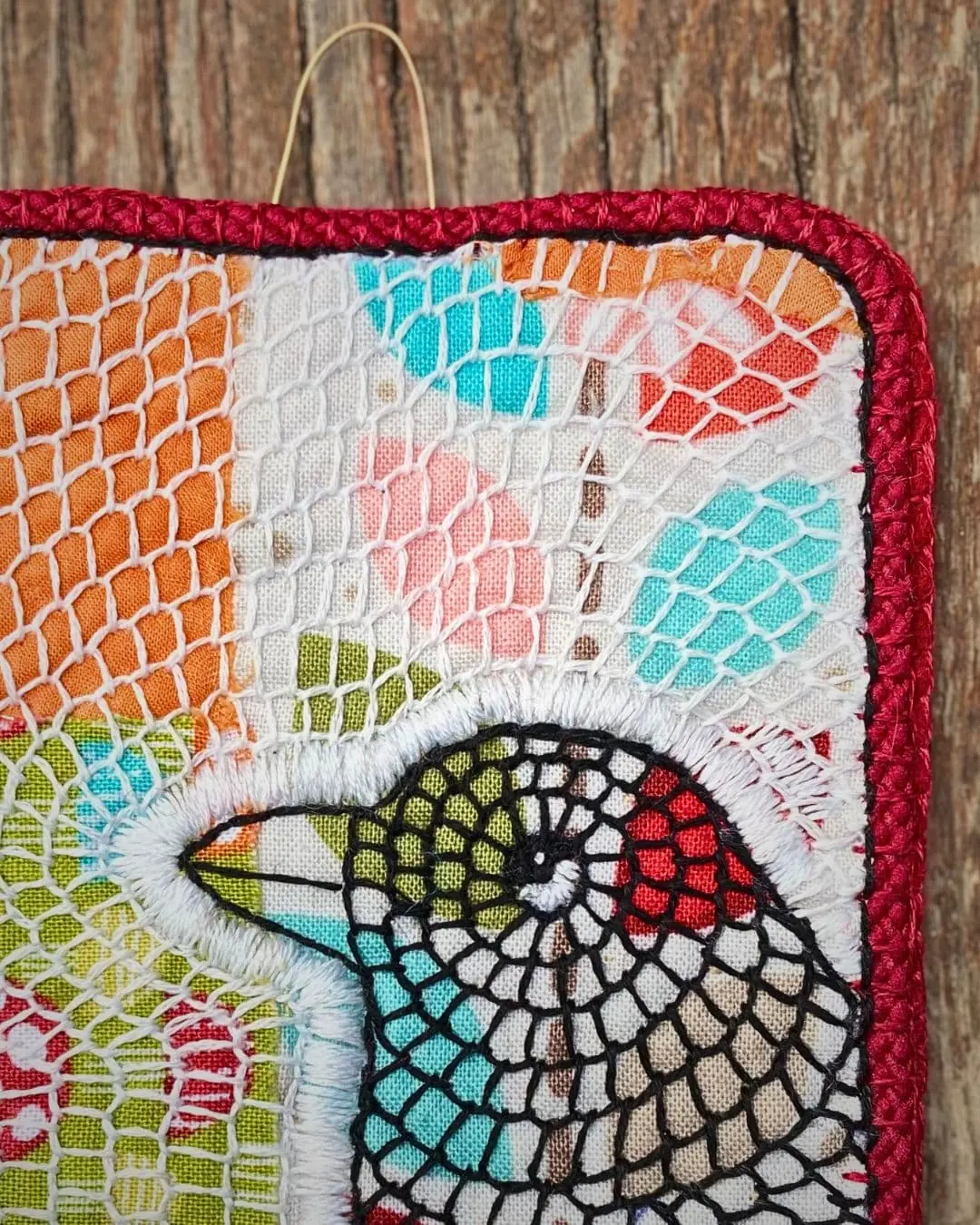 A hand embroidered fabric collage of a blackbird.