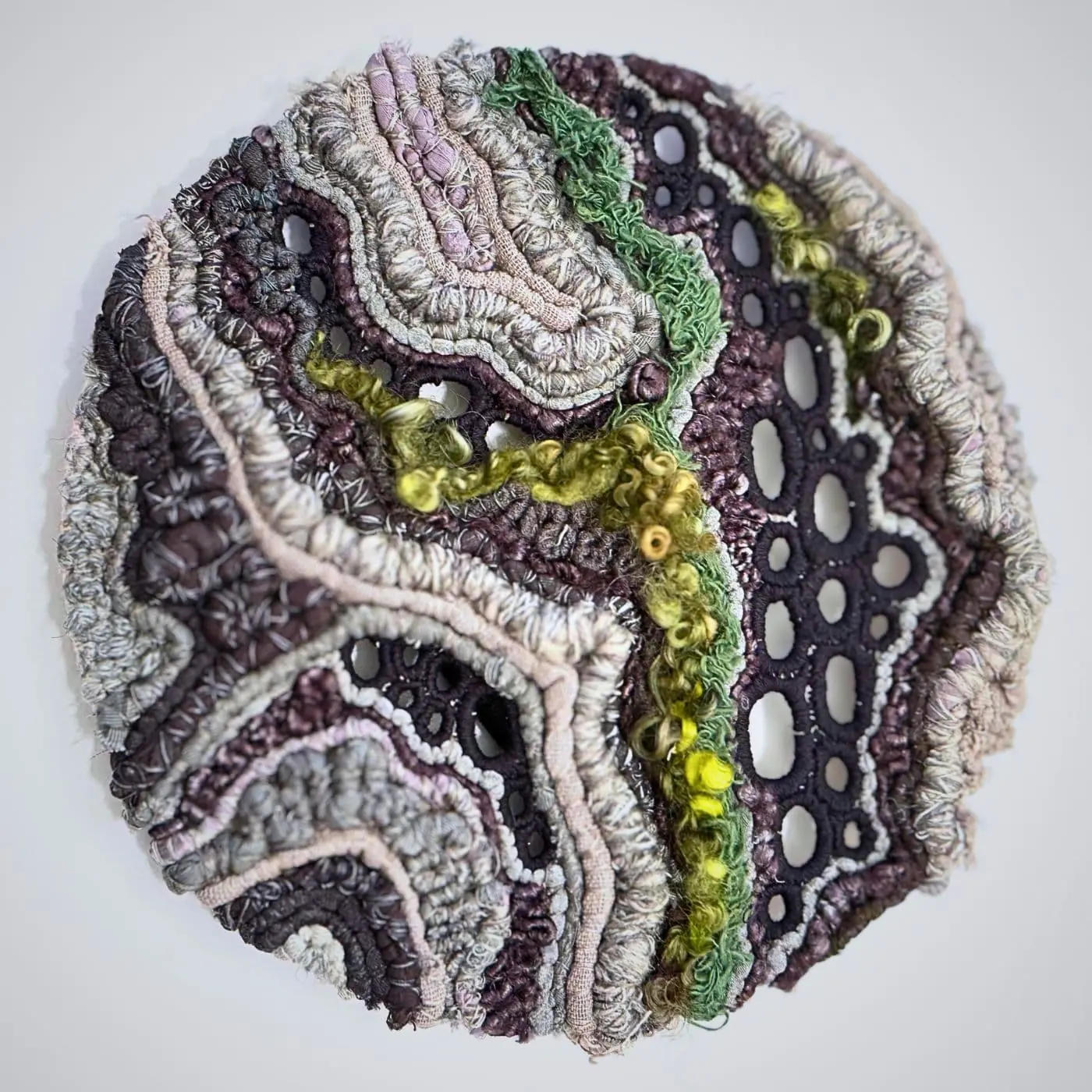 A close up of an embroidered artwork using various threads.