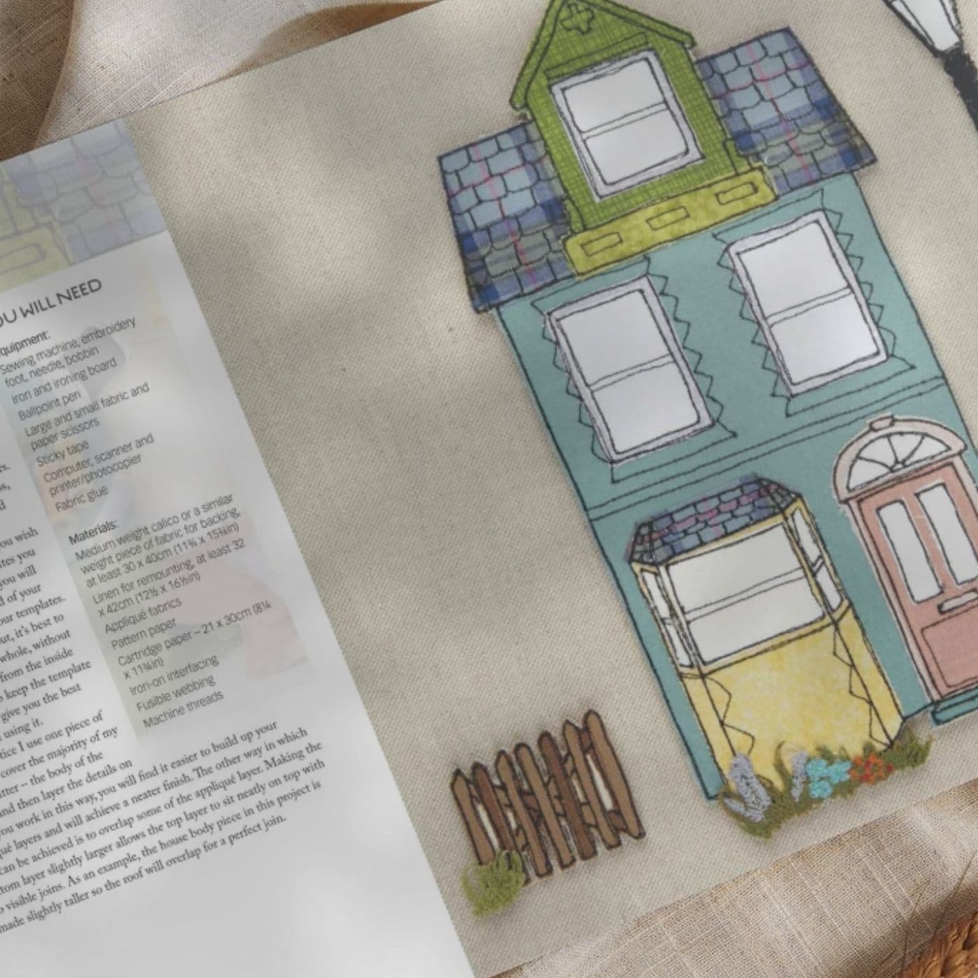 Inside of book with writing and an embroidered picture of a house