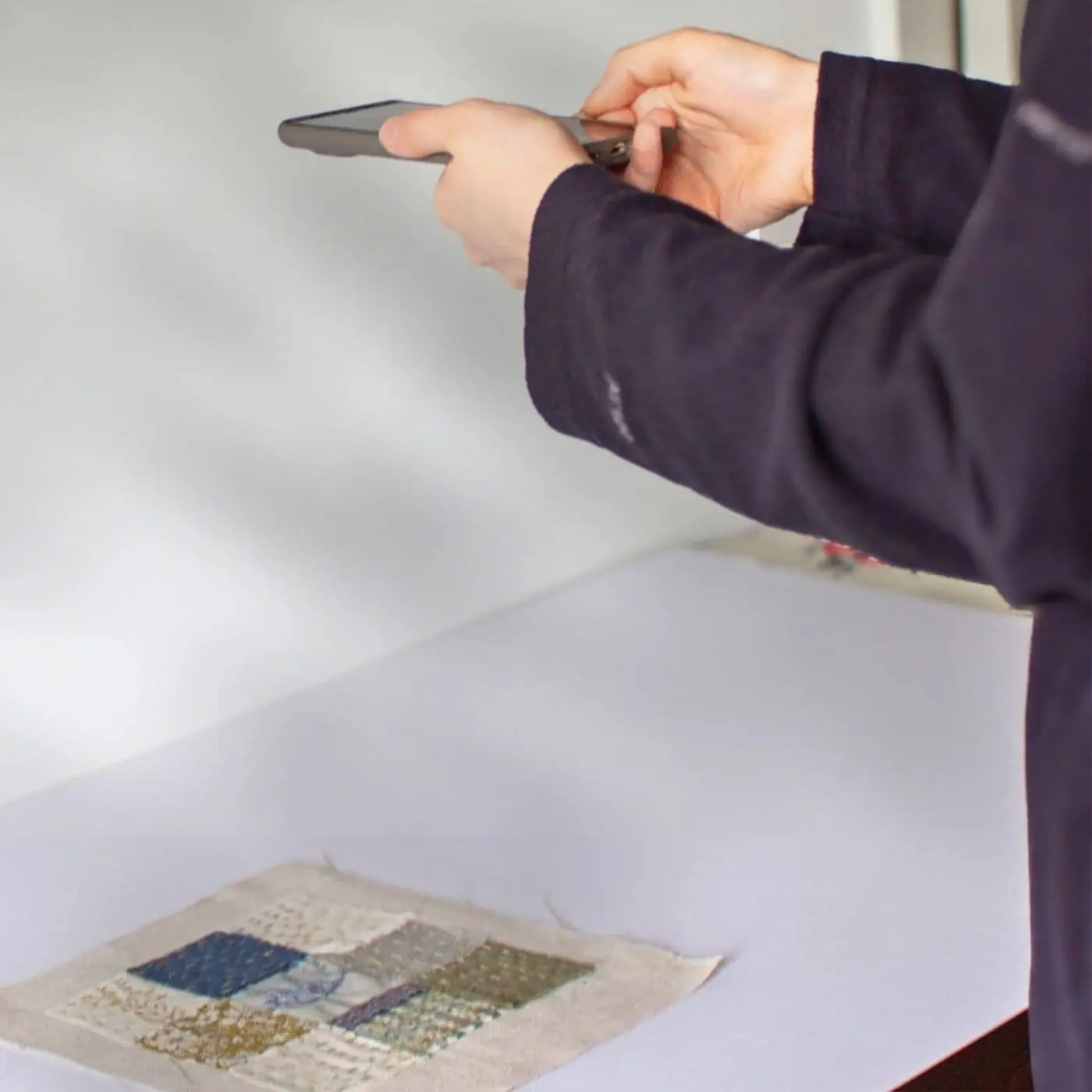 A person taking a picture of a piece of textile art with a smartphone