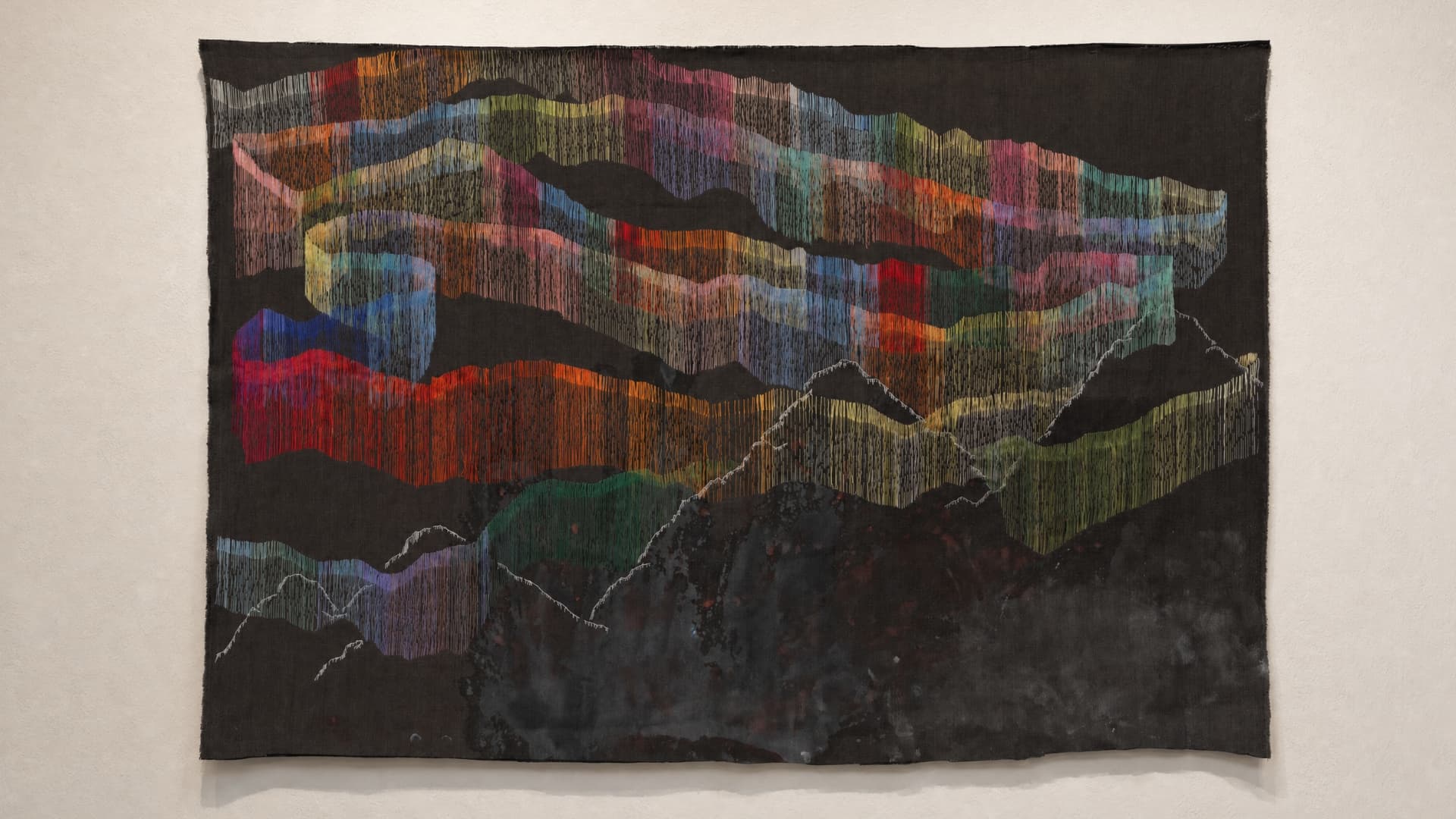Abstract colourful textile art piece hanging on wall in gallery