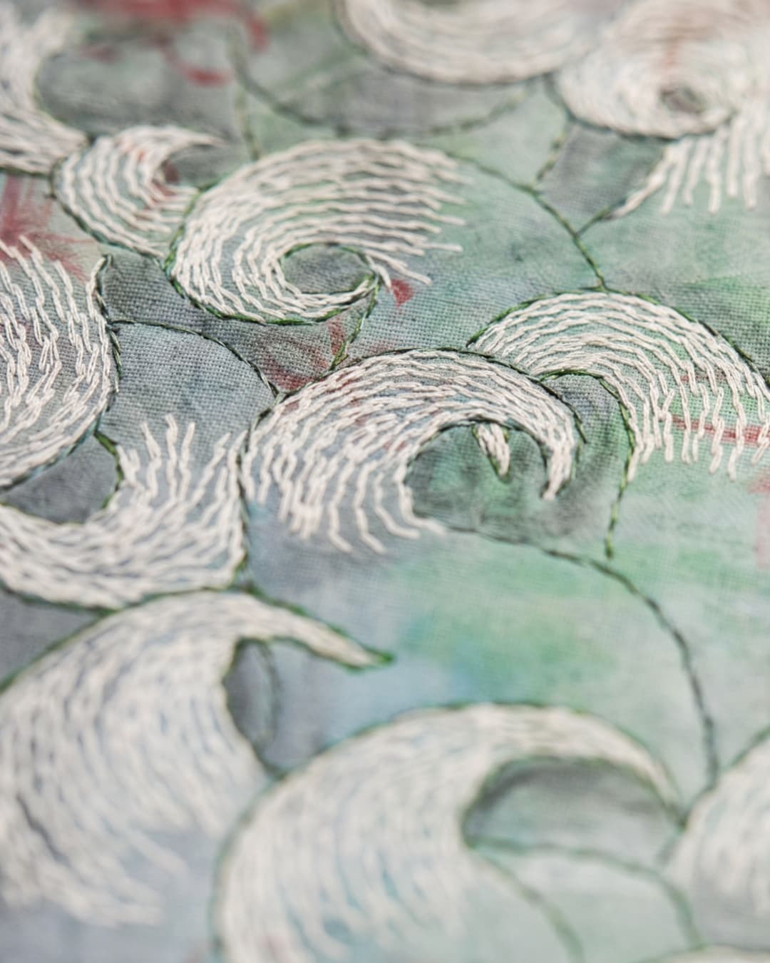 Intricate embroidered waves on fabric.