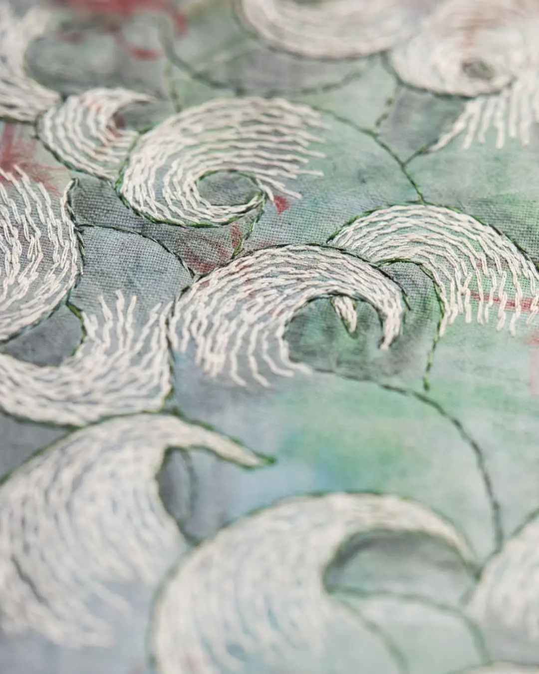 Intricate embroidered waves on fabric.
