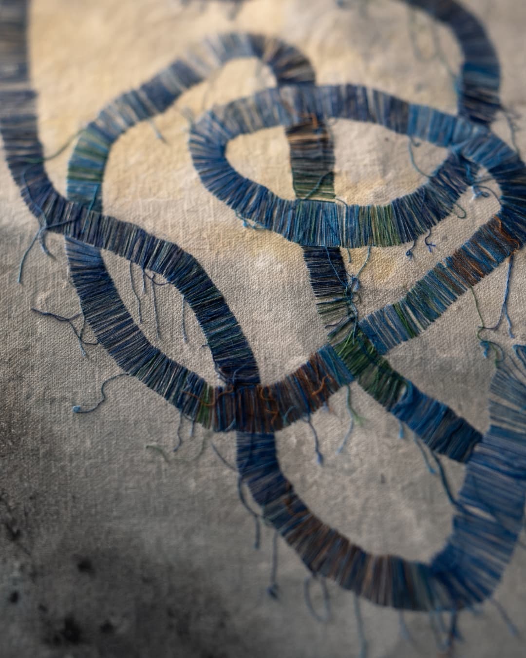 Intricate blue thread loops on fabric.