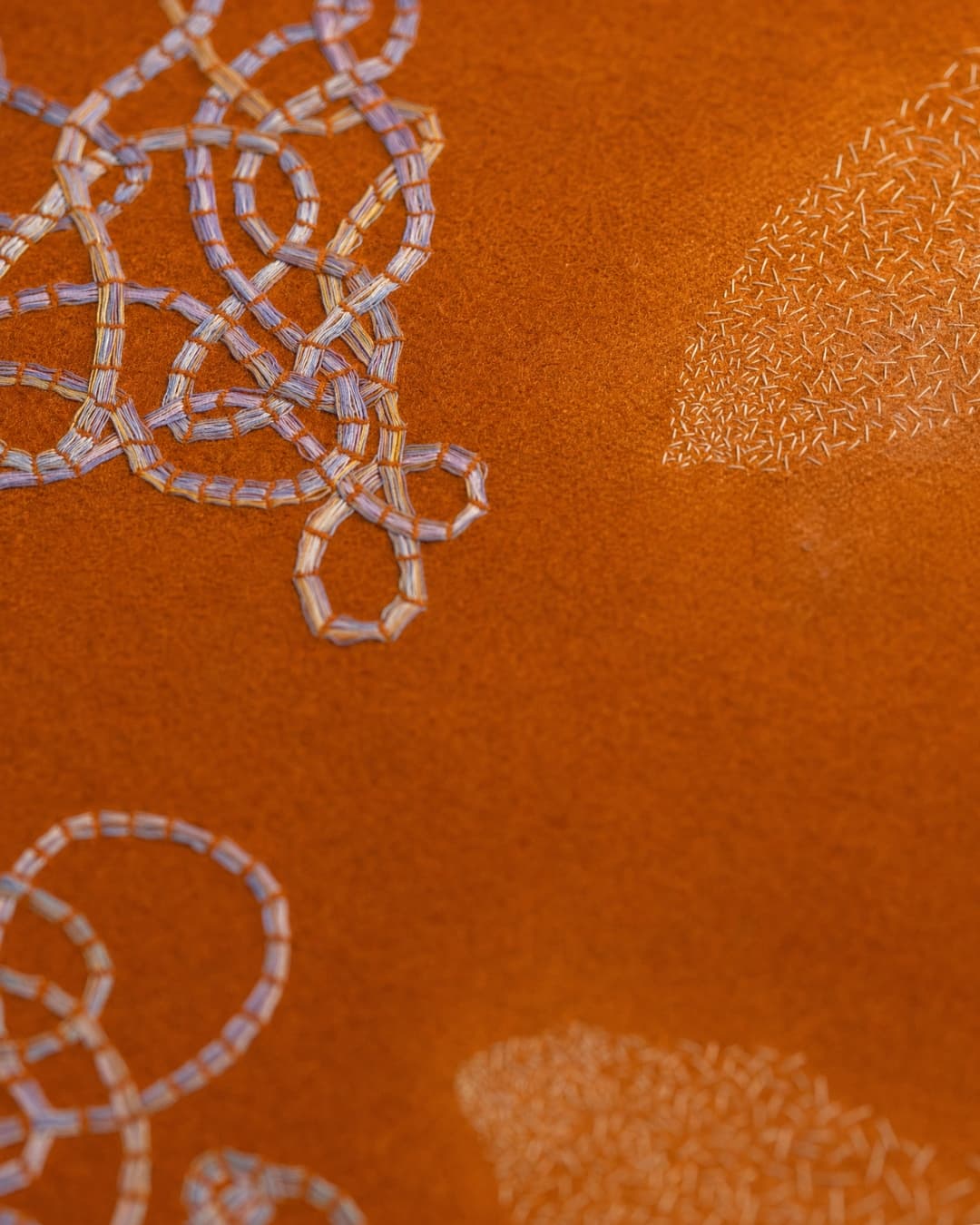 Intricate embroidery on textured orange background.