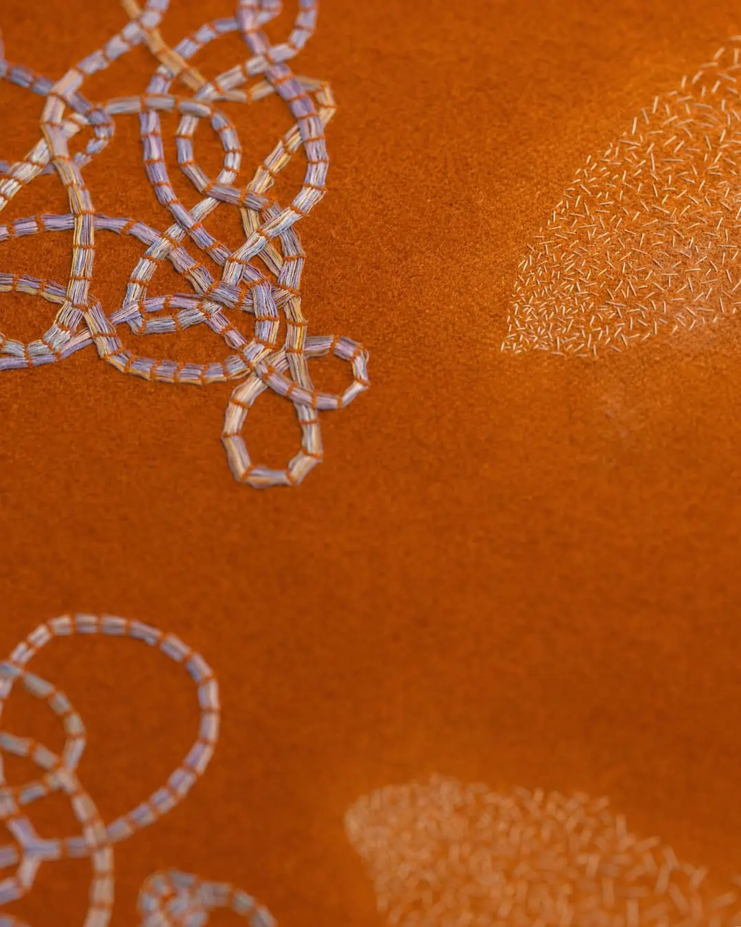 Intricate embroidery on textured orange background.
