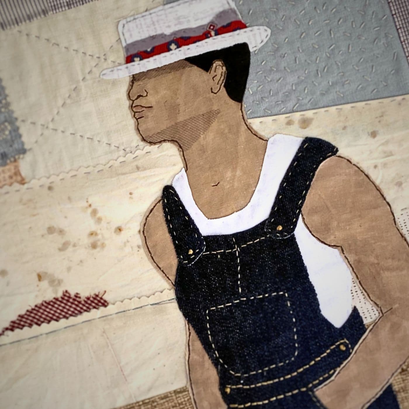 A fabric hand stitched collage of a man in a hat.