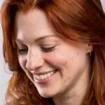 A close up image of textile artist Meredith Woolnough, smiling whilst working on a new artwork.