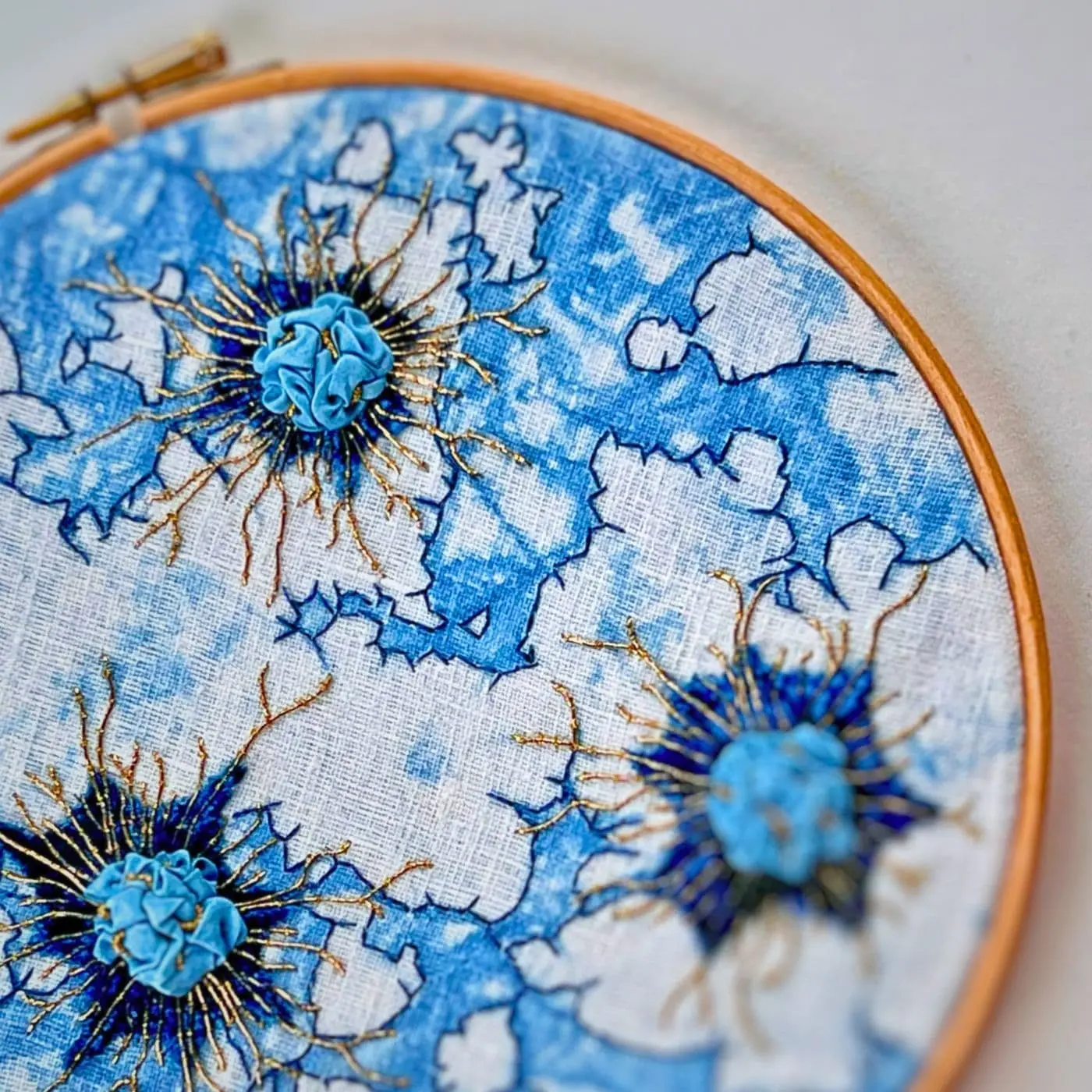 An embroidery hoop with blue and white textile art piece