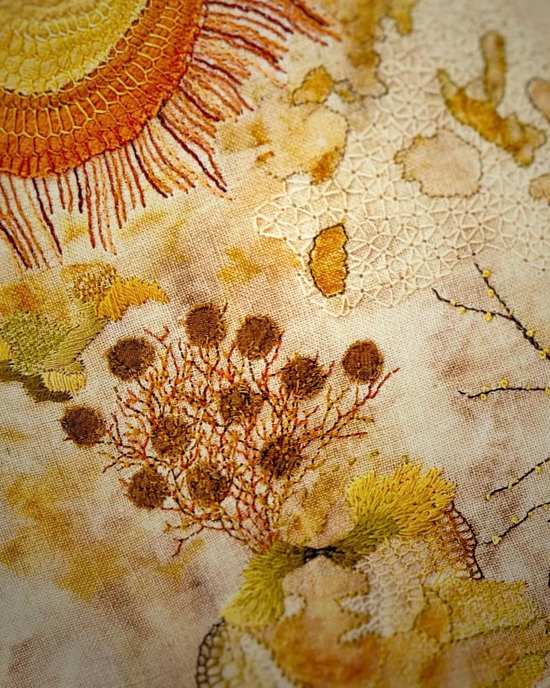 A Stitched piece of art featuring a sun and plants