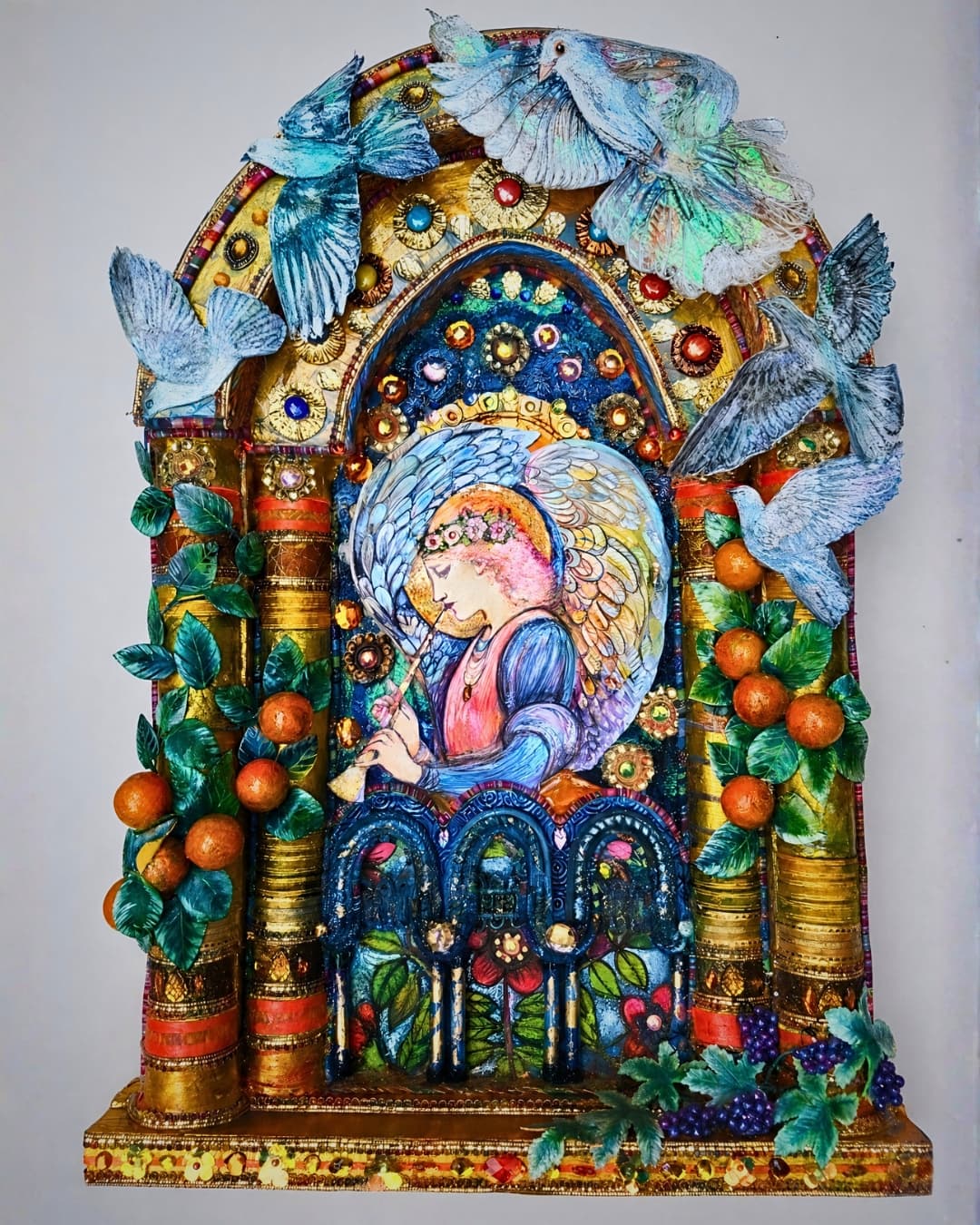 Colourful textile angel surrounded by birds and fruit