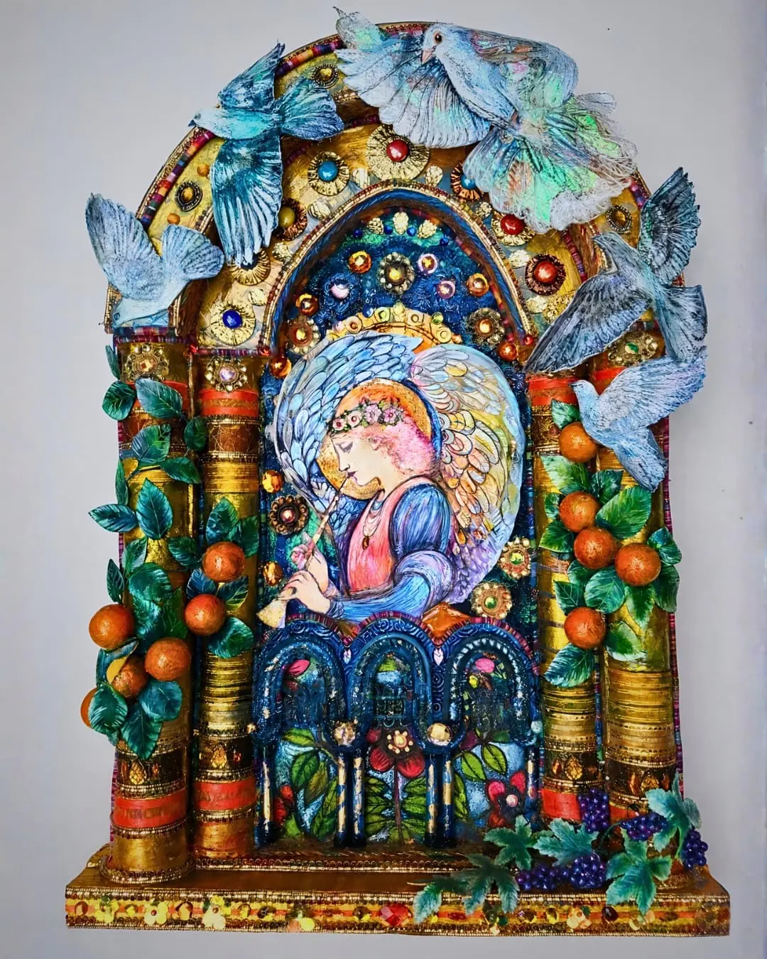 Colourful textile angel surrounded by birds and fruit