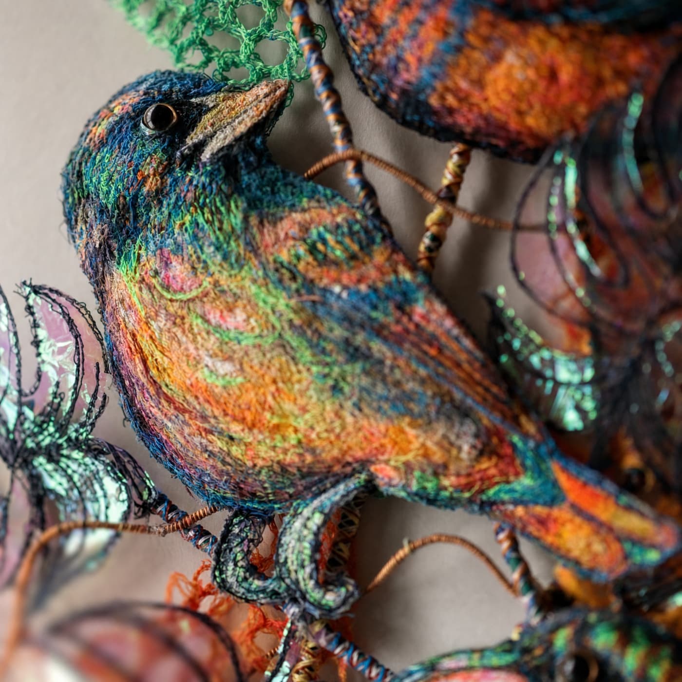 Colourful embroidered bird on foliage