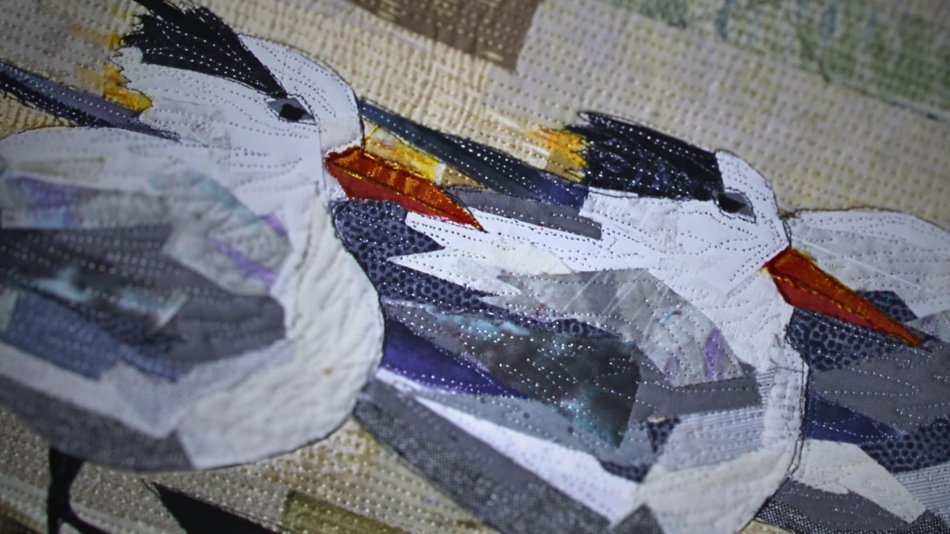 A close up of a quilt of a trio of birds