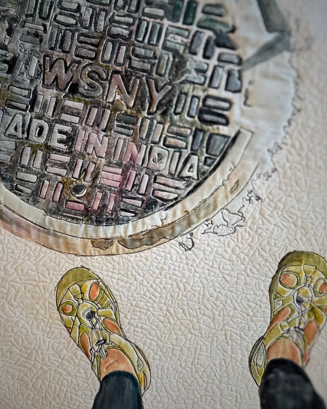 Stitched artwork of a pair or feet next to a New York street vent