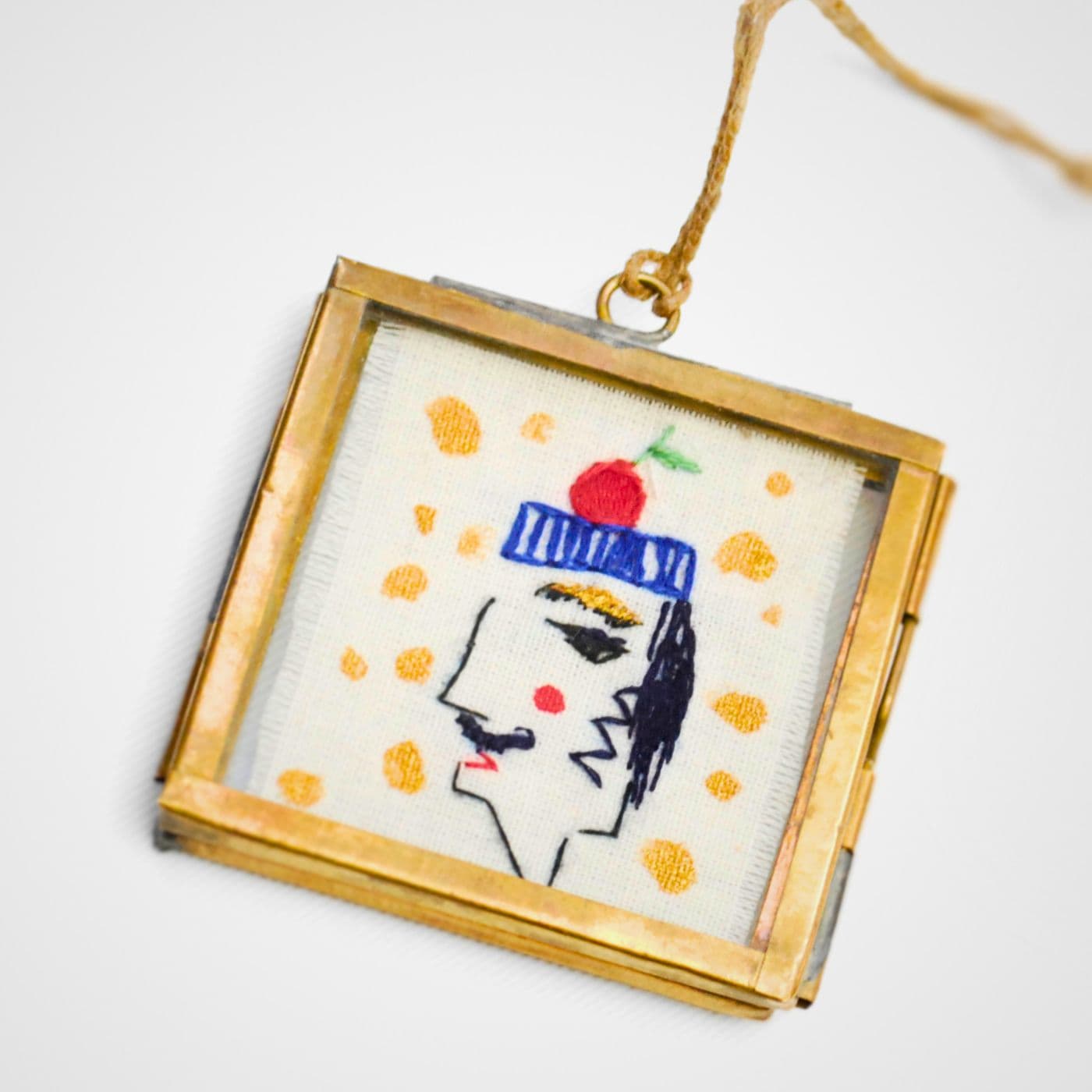 A gold frame with a stitched portrait of a man with an apple on his head