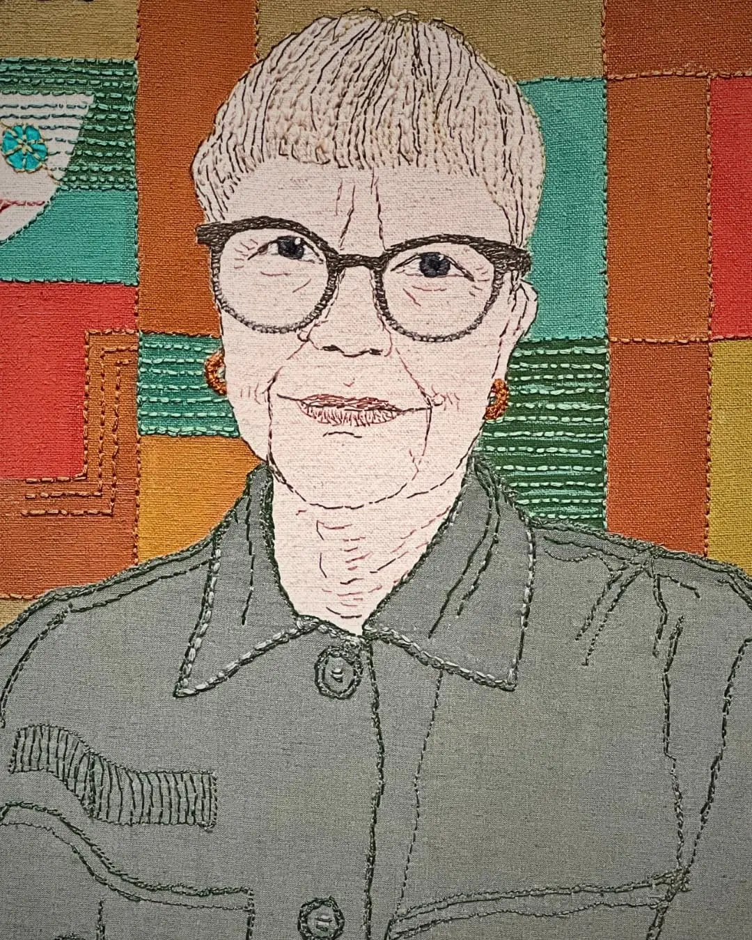 Colourful textile art with embroidered figure.