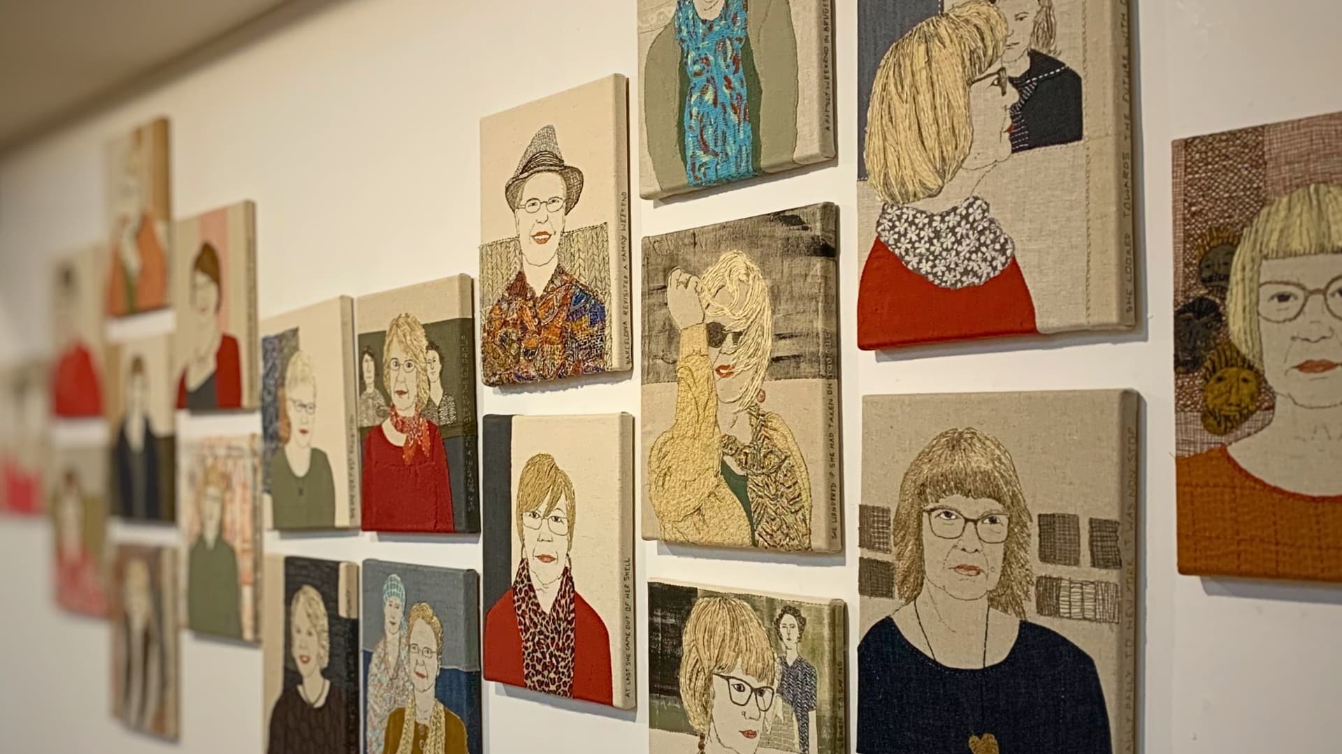 Textile artworks featuring stylised human figures on display in a gallery.