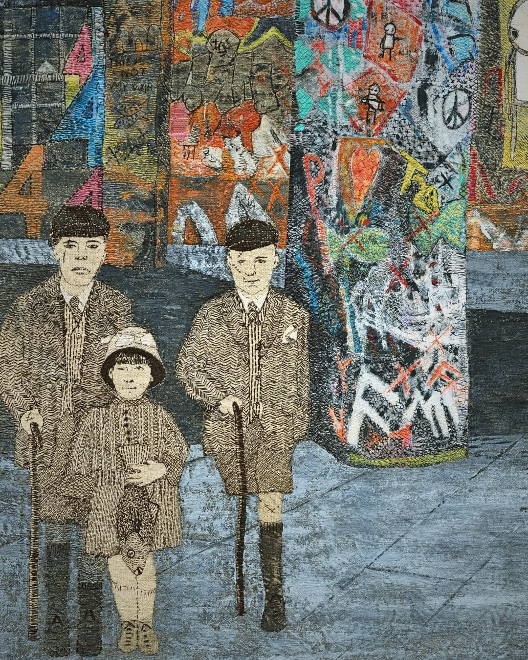 Textile art piece with three figures in vintage clothing walking in front of graffitied wall.