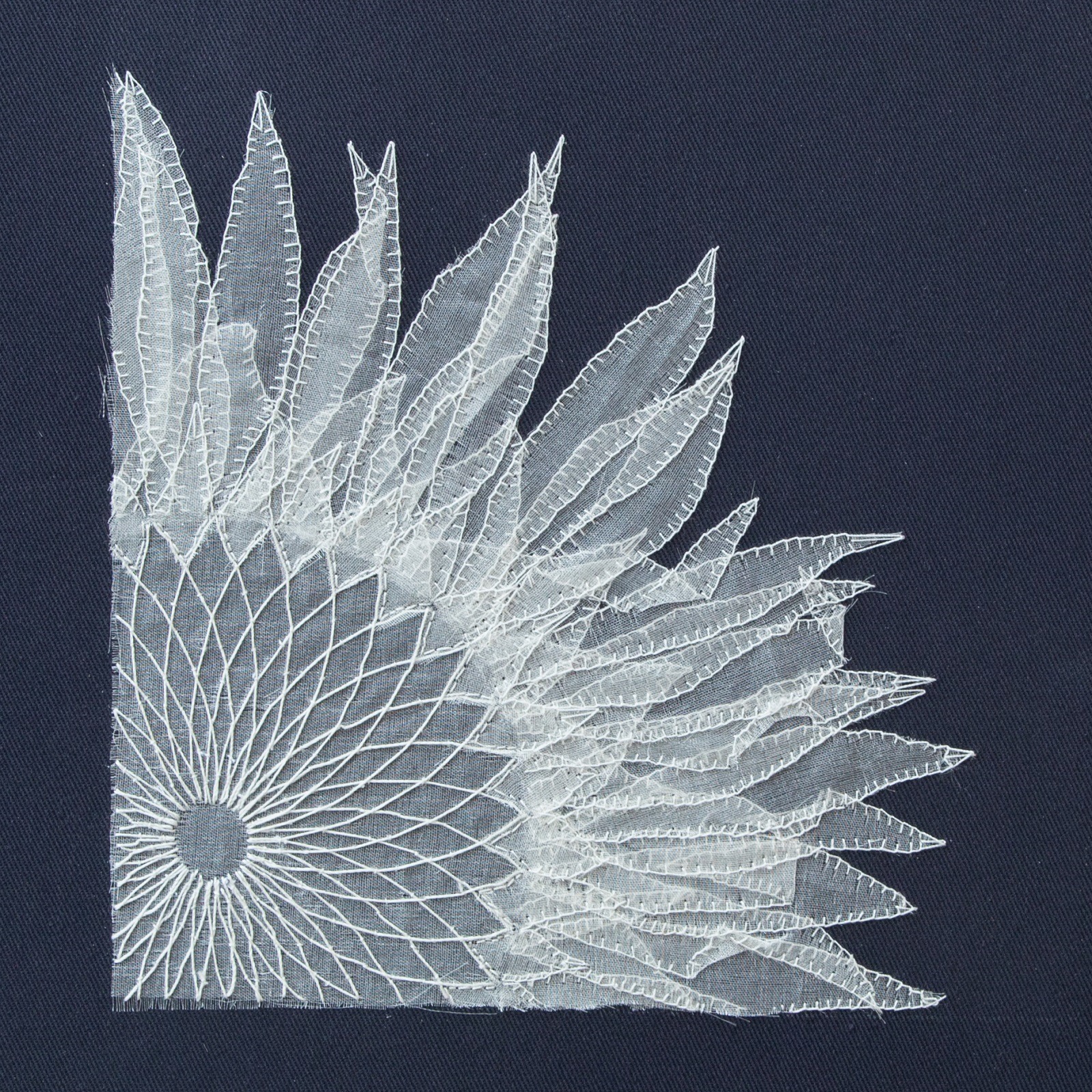 A white lace sunflower design on a blue fabric surface