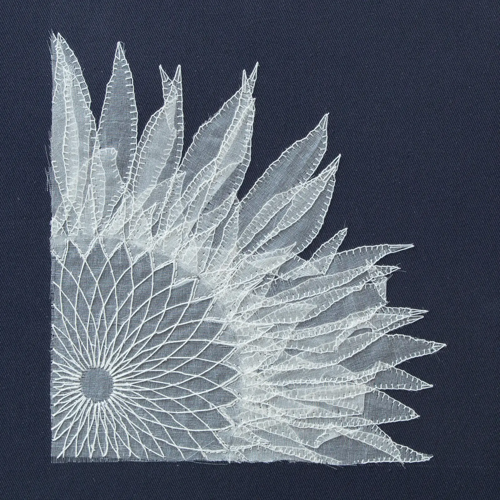 A white lace sunflower design on a blue fabric surface