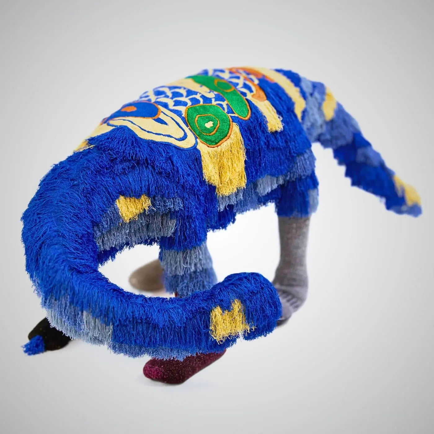 A stitched artwork of a Dinosaur embellished with colourful yarn.