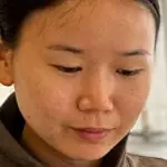A close up of textile artist Woo Jin Joo, focussed on the creation of her work