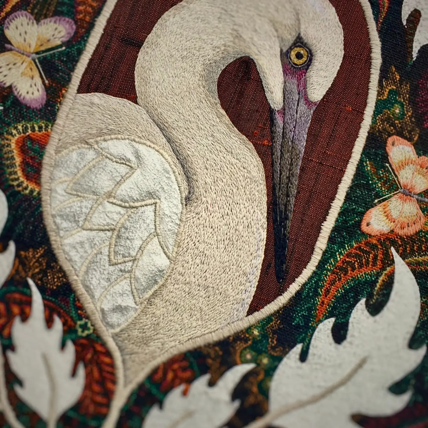 An embroidery of a white bird with a butterfly on it.